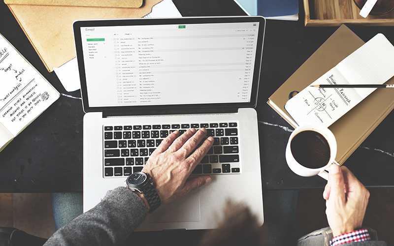 man typing emails on laptop