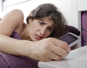 woman checking phone in bed
