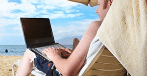 man working on laptop while on beach