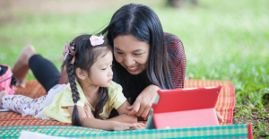 mom and daughter using tablet in park