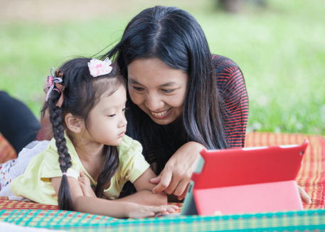 mom and daughter using tablet in park