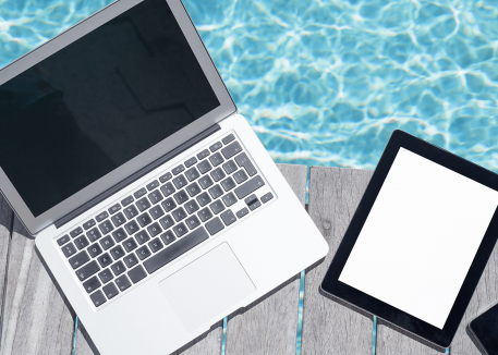 computer, tablet, and phone on deck next to pool