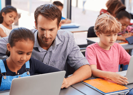 teacher works with students on secure laptops