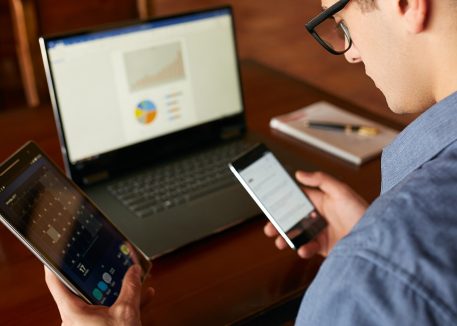 a man distracted by technology tries to work on multiple devices at once