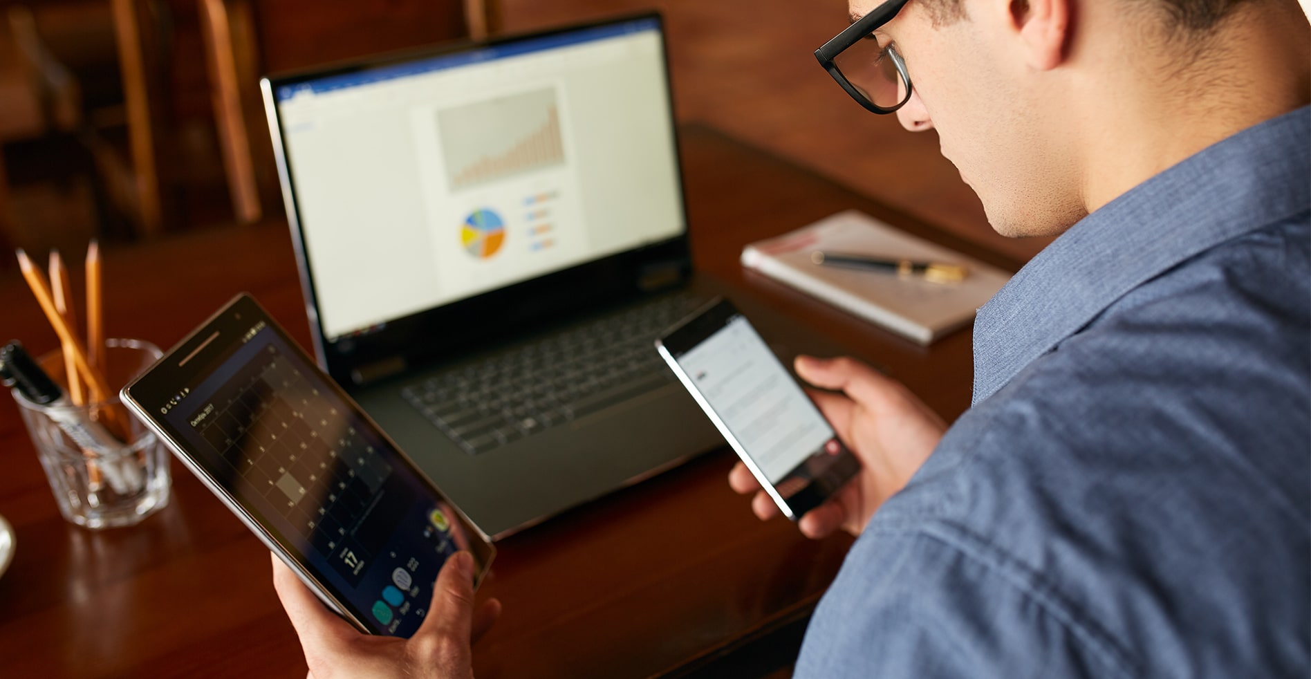 a man distracted by technology tries to work on multiple devices at once