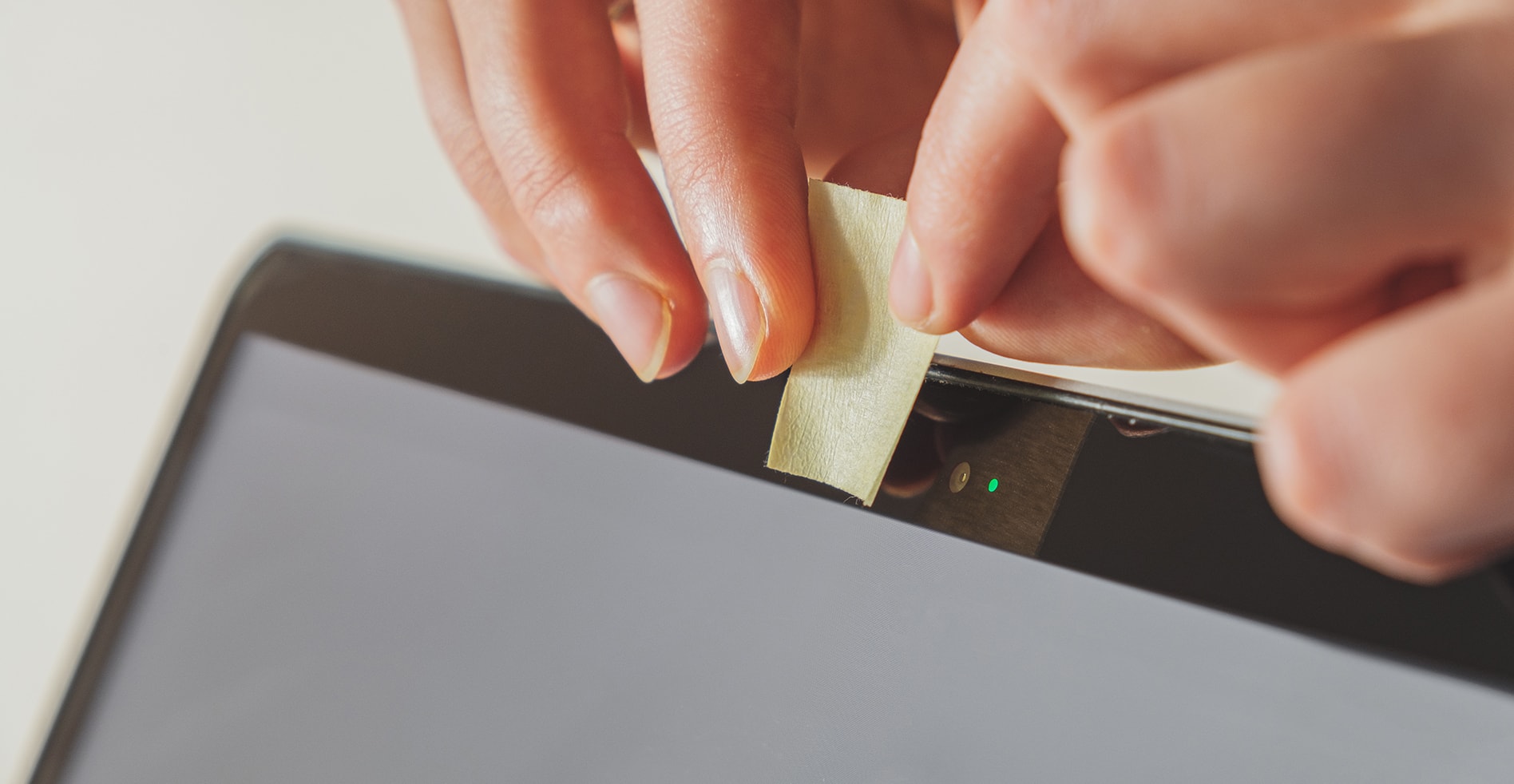 hands cover laptop camera with sticky note