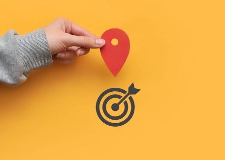 hand holding a map pin over a bullseye to illustrate geofencing